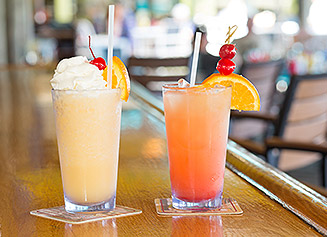 Two tropical cocktails on a wooden bar top
