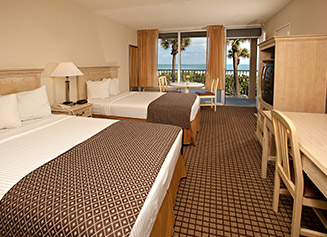 Two queen beds with white linens and brown diamond patterned duvets
