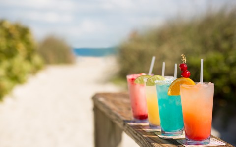 Colorful cocktails on wooden ledge by the beach 