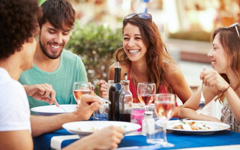 Group of friends eating at table with wine 