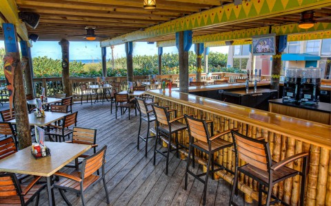 Outdoor seating area with with tables chairs & bar with stools 
