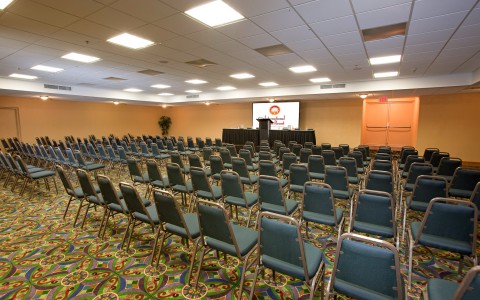 Event space with projection screen and rows of chairs 